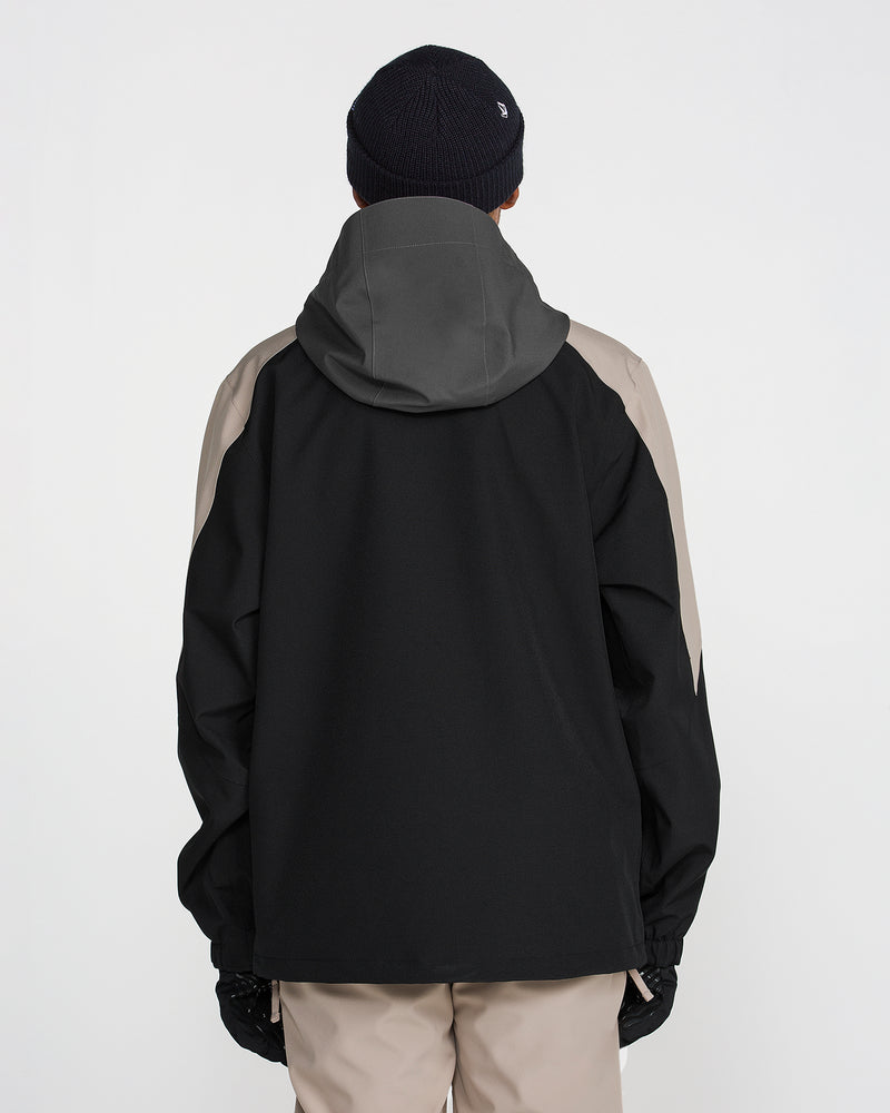 A person facing away, wearing the Volcom Men’s Brighton Full Zip Jacket in black and taupe—featuring V-Science 2-Layer construction and PFAS-free DWR—paired with beige pants, black gloves, and a dark knit beanie, against a plain white background.
