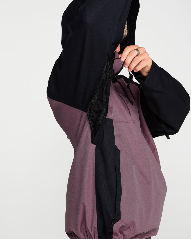 A person wearing the Volcom Men’s Hossegor 20K Pullover unzips the side ventilation opening under the arm, revealing the black interior lining of the recycled V-Science shell; only their arm and hand are visible.