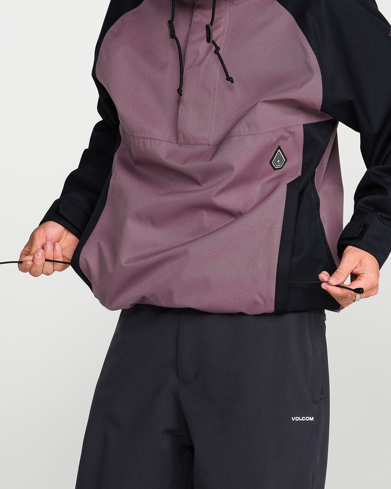 Wearing the Volcom Men’s Hossegor 20K Pullover, which features a two-tone maroon and black design and is crafted with a recycled V-Science shell, a person in dark pants pulls the drawstrings at the jacket’s hem. Their face remains out of view.