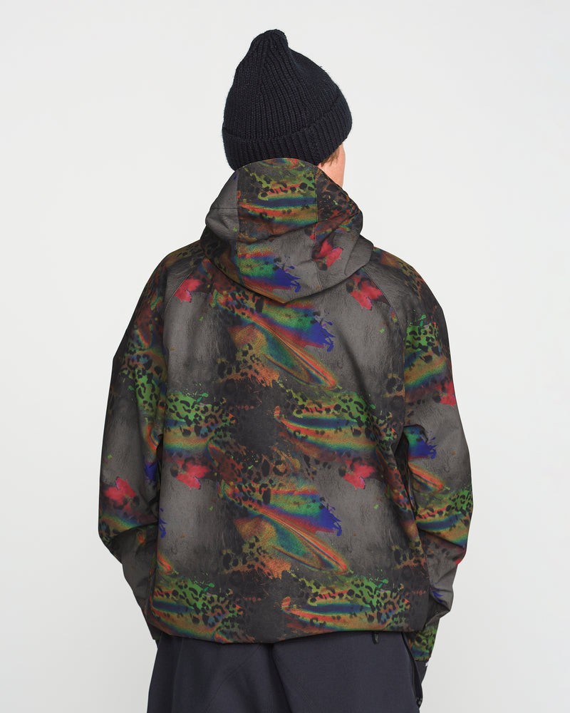A person wearing a black knit beanie and the Volcom Men’s Hossegor 20K Pullover—a hooded jacket featuring a colorful, abstract pattern crafted from recycled V-Science shell—stands facing away against a plain white background.