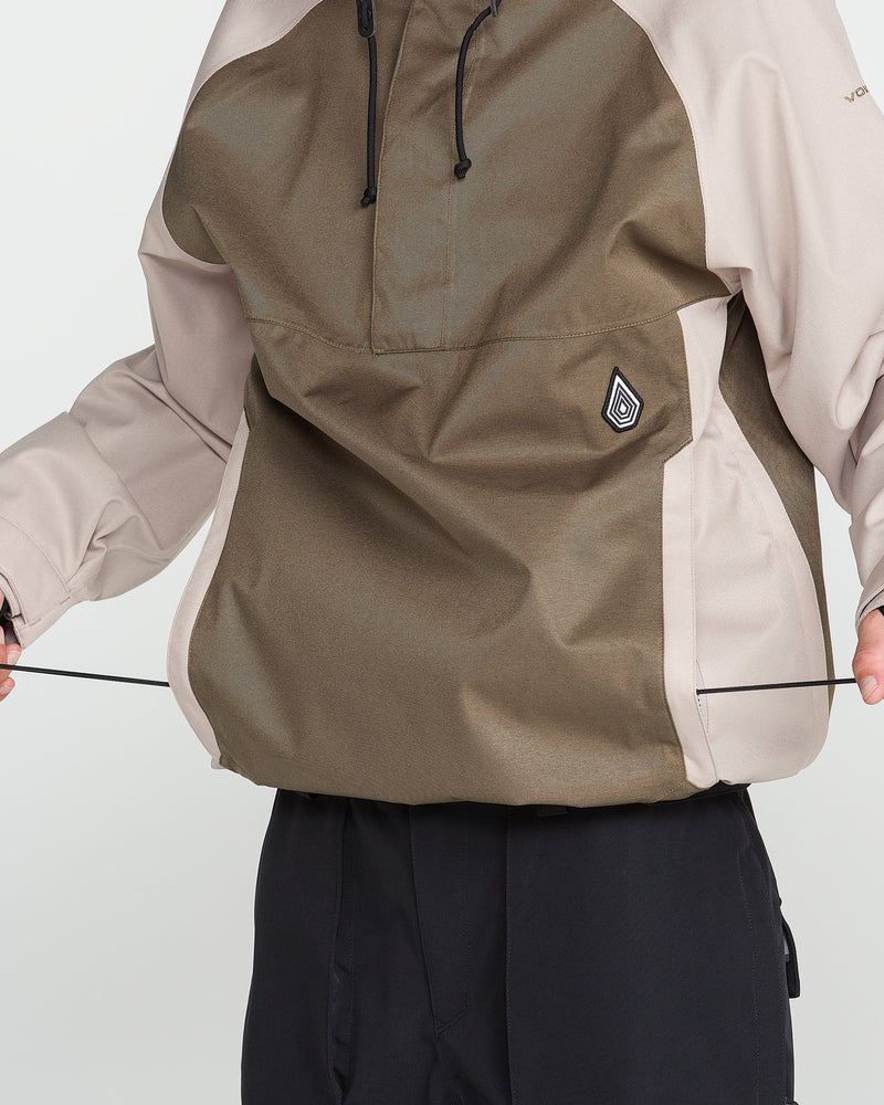 A person adjusts the drawstrings on the hem of a brown and beige Volcom Men’s Hossegor 20K Pullover jacket while wearing black pants, with emphasis on the front and lower half of the jacket.