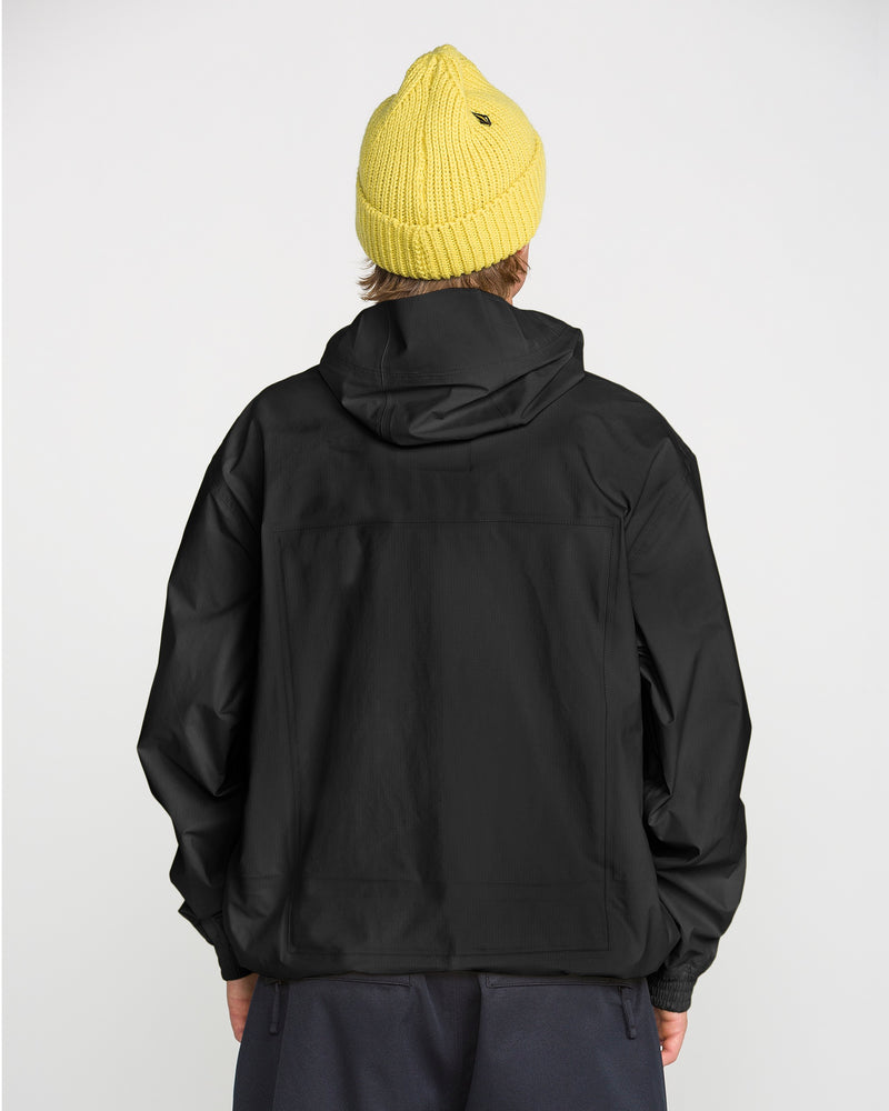 A person faces away from the camera, wearing a yellow knit beanie, dark pants, and the Volcom Men’s Arthur 3L 20K Jacket—a black hooded jacket with V-Science 3-Layer storm-grade protection—set against a plain white background.