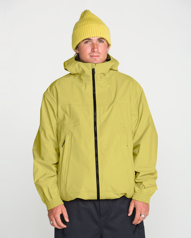 A person wearing a yellow Volcom Men’s Arthur 3L 20K Jacket with a black zipper and a matching yellow beanie, standing against a plain white background.