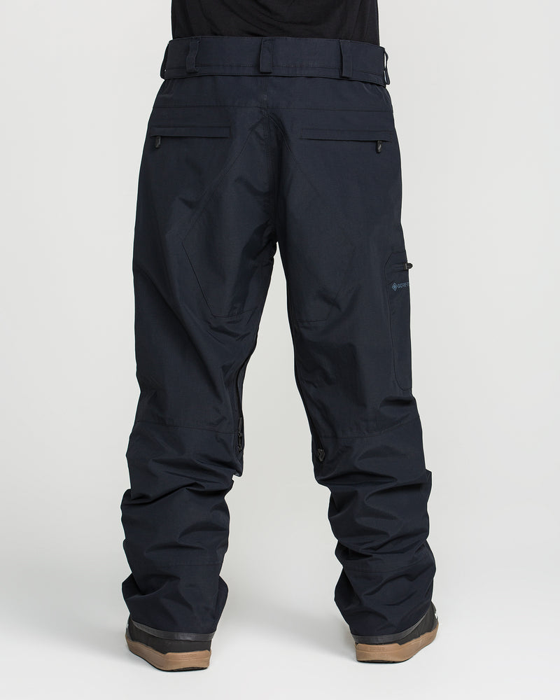 A person wearing black Volcom Men’s L Gore-Tex Pants and brown boots, shown from the back against a plain white background.