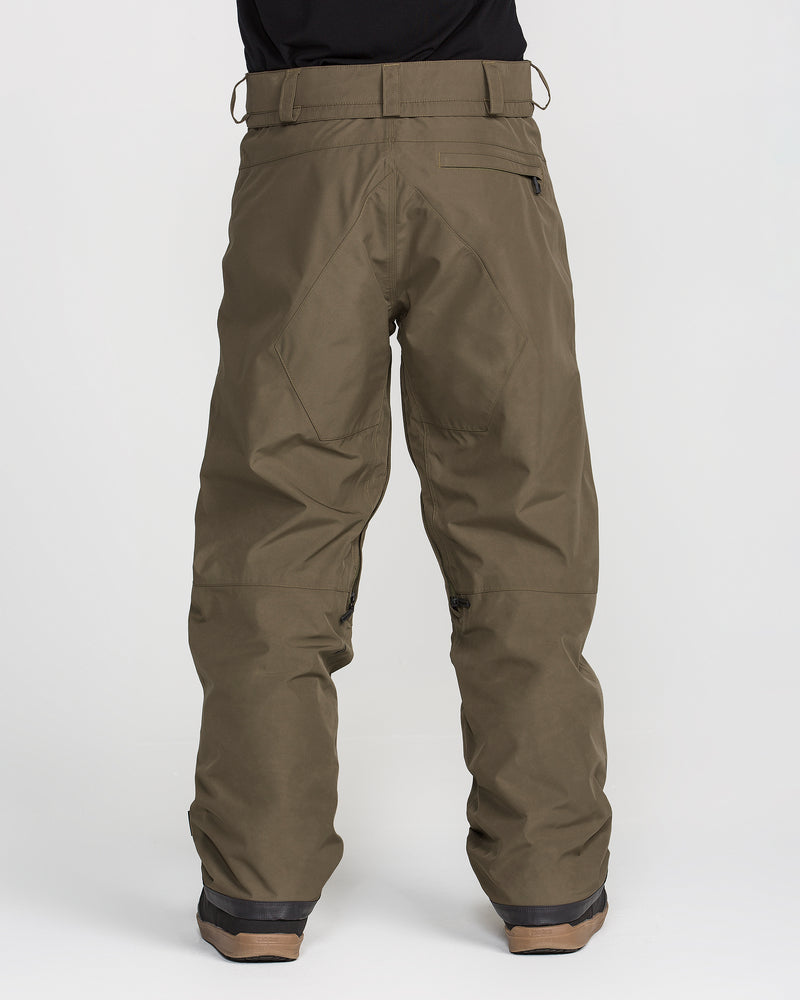 A person is shown from the back against a plain white background, wearing Volcom Men’s Dua Gore-Tex Pants in brown, which feature a breathable lining and a loose fit, paired with dark boots.