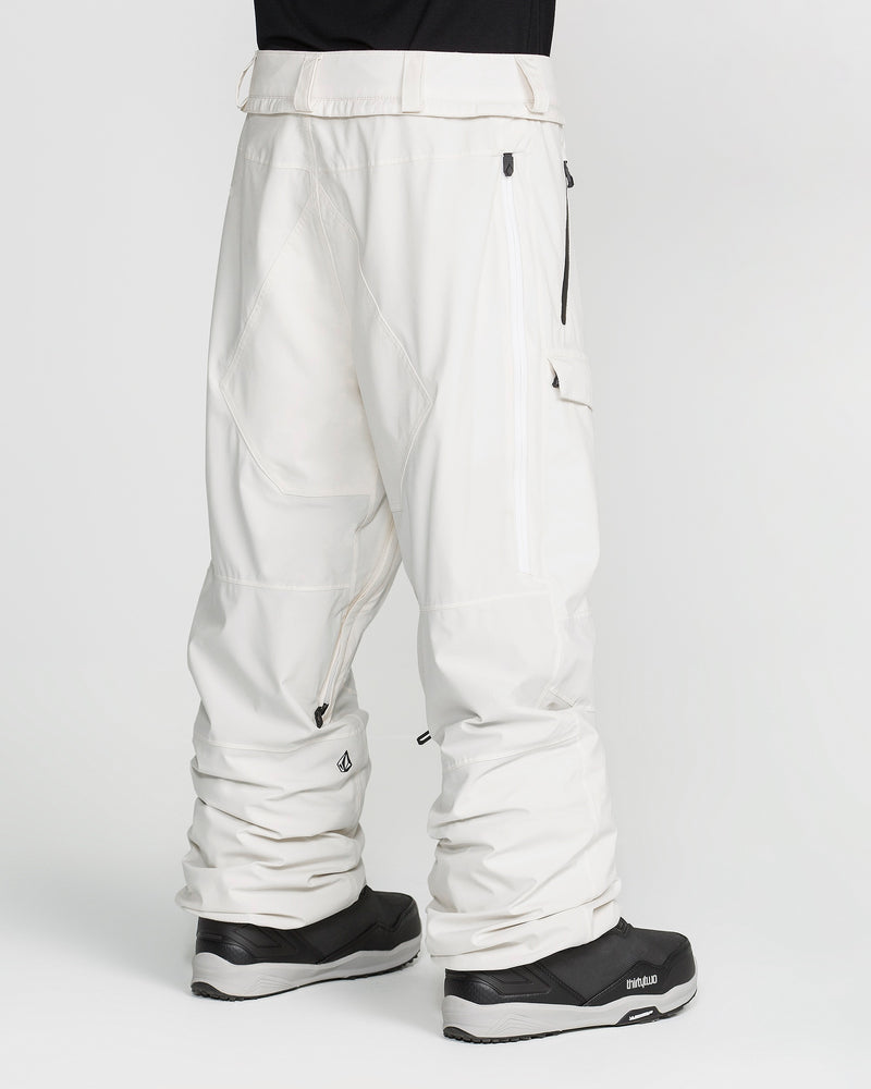 A person wearing Volcom Men’s Rnge Stretch 30K Pants in a loose, baggy fit with zippered pockets, paired with black snow boots, is photographed from the back against a plain white background.