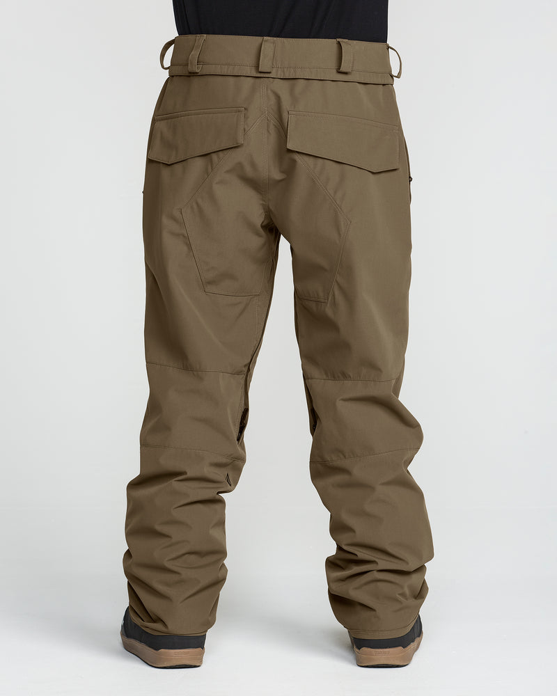 A person wearing the Volcom Men’s Roan 20K Pants in olive-green, paired with black shoes, is shown from the back. Made from recycled fabric, these pants feature back flap pockets and reinforced stitching on the legs. The background is plain white.