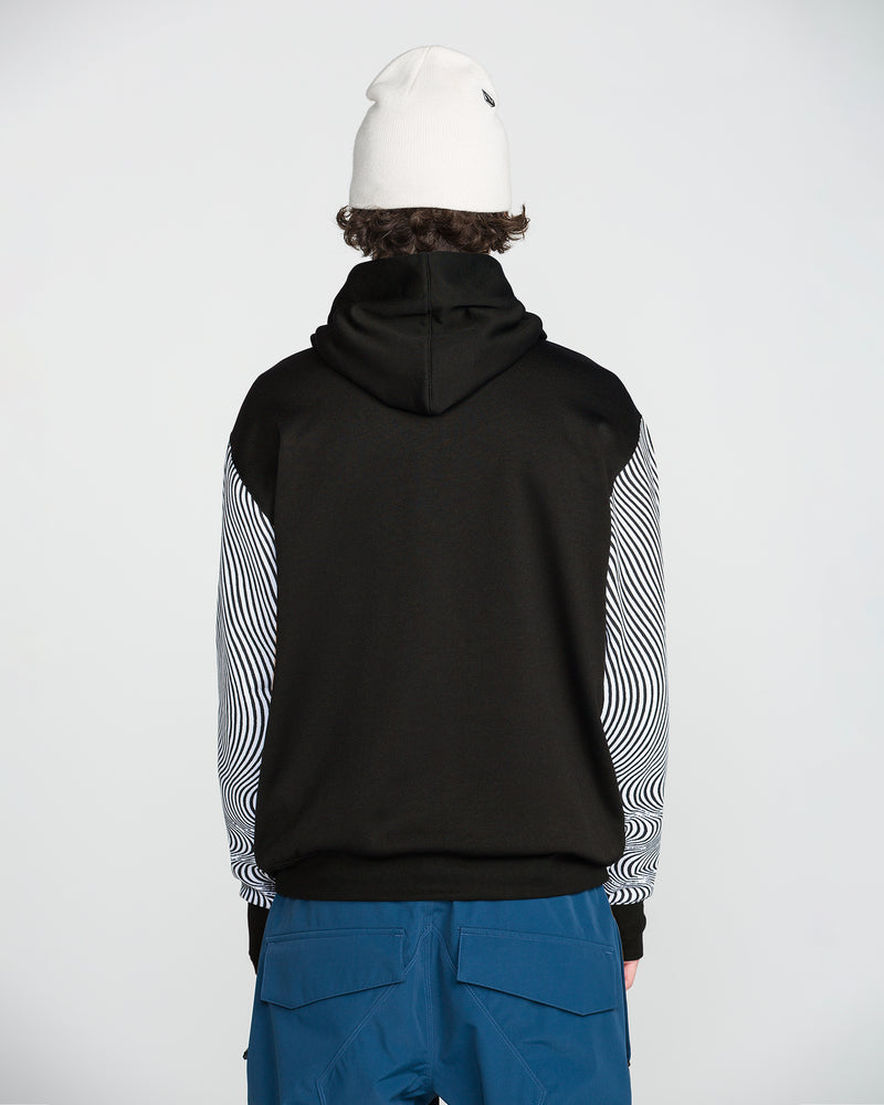 A person is standing with their back to the camera against a plain background, wearing a white beanie, blue pants, and the Volcom Men’s Hydro Riding Hoodie—a black hoodie made from hydrophobic fleece with striped sleeves.