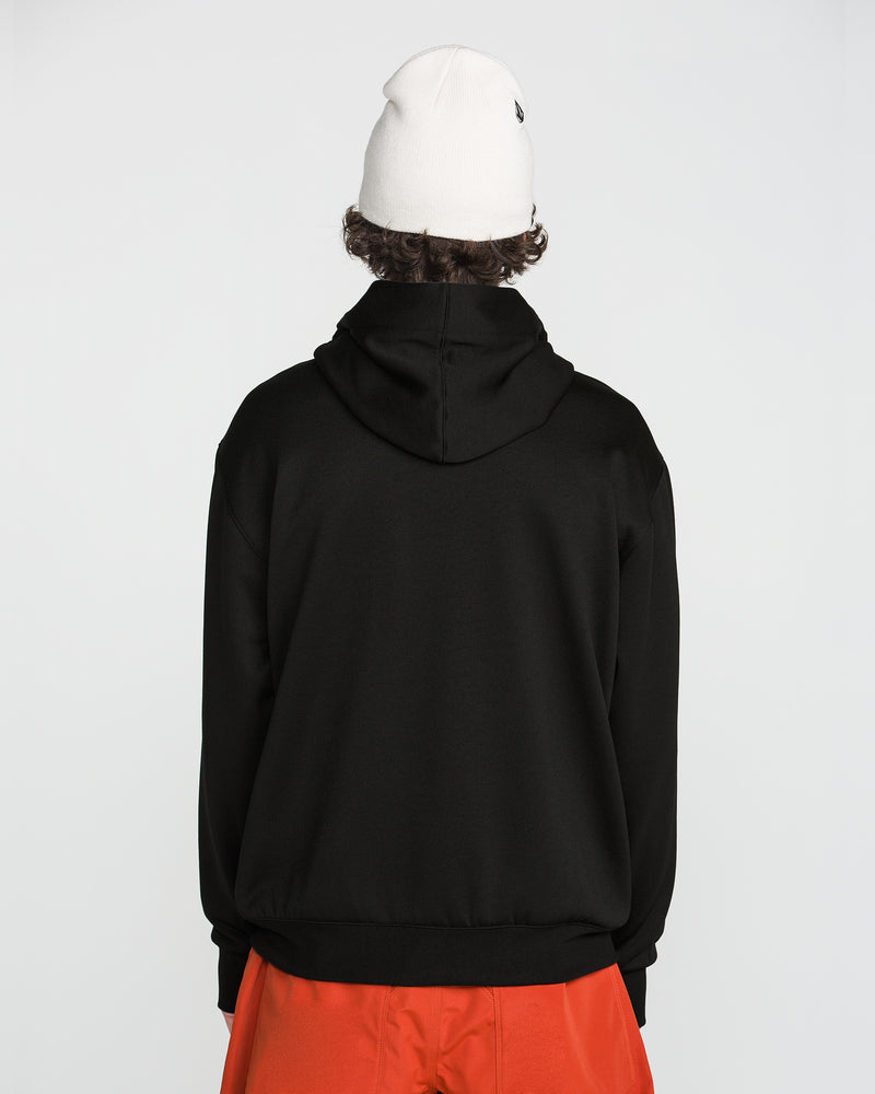 A person stands facing away, wearing the Volcom Men’s Hydro Riding Hoodie in black, an off-white beanie, and bright orange pants against a plain white background.