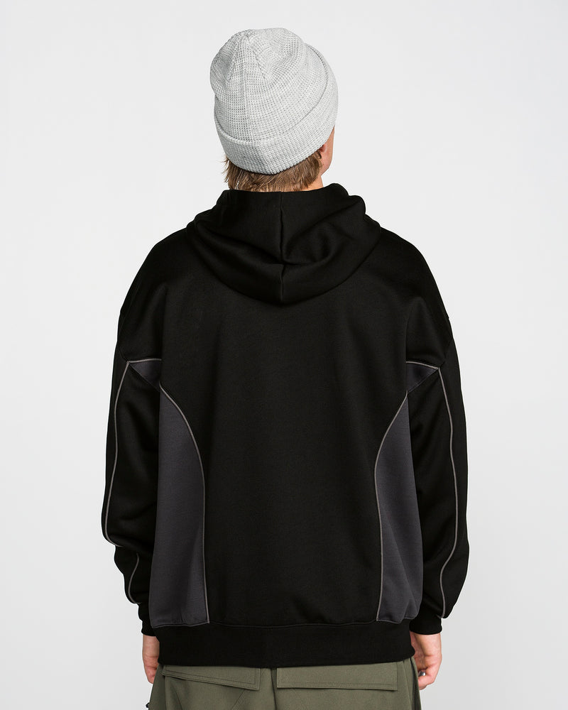 A person is standing with their back to the camera against a plain white background, wearing a light gray knit beanie, olive green pants, and the Volcom Men’s Vital Hydro Pullover Hoodie in black with dark gray side panels.