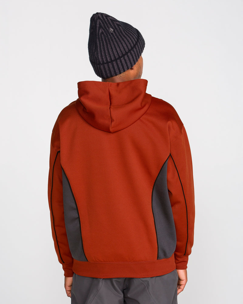 A person is standing with their back to the camera against a plain white background, wearing the Volcom Men’s Vital Hydro Pullover in red with dark gray side panels and a black knitted beanie.
