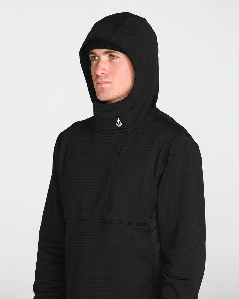 A man stands against a plain white background, looking slightly to the side, dressed in the Volcom Men’s Gridlock Hooded Pullover in black—a midweight fleece featuring a small white Volcom logo at the neck.