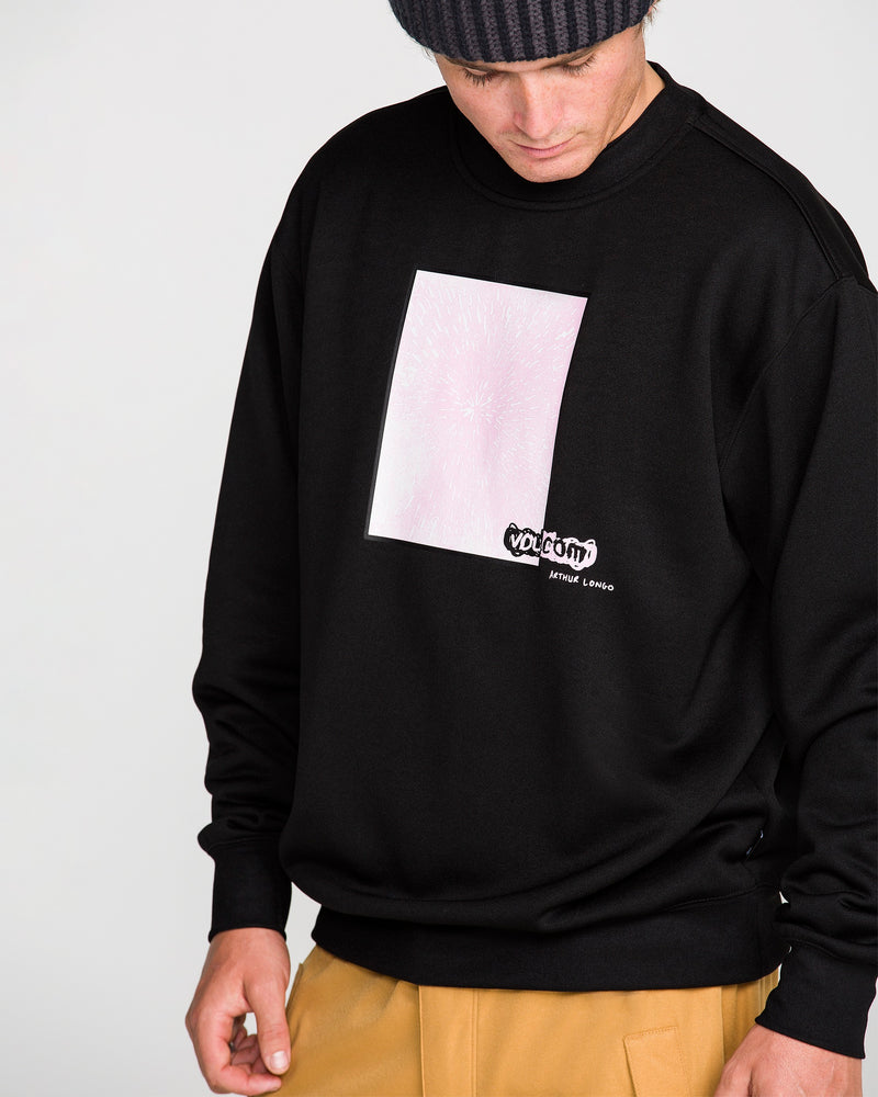 A person wearing the Volcom Men’s Hydro Crew, a black sweatshirt featuring a white and pink rectangular design and text, paired with light brown pants and a black beanie, looking down.