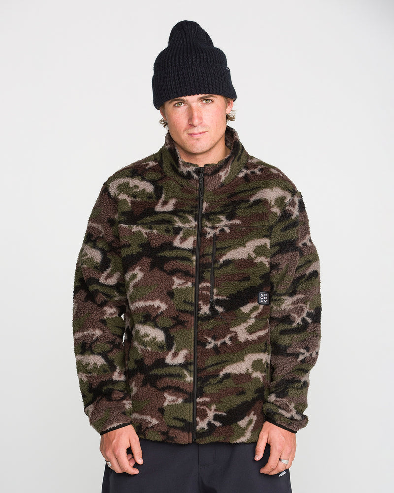 A person wearing a black beanie and the Volcom Men’s Nelson Sherpa Full Zip in green camouflage stands against a plain white background, looking directly at the camera with a neutral expression.