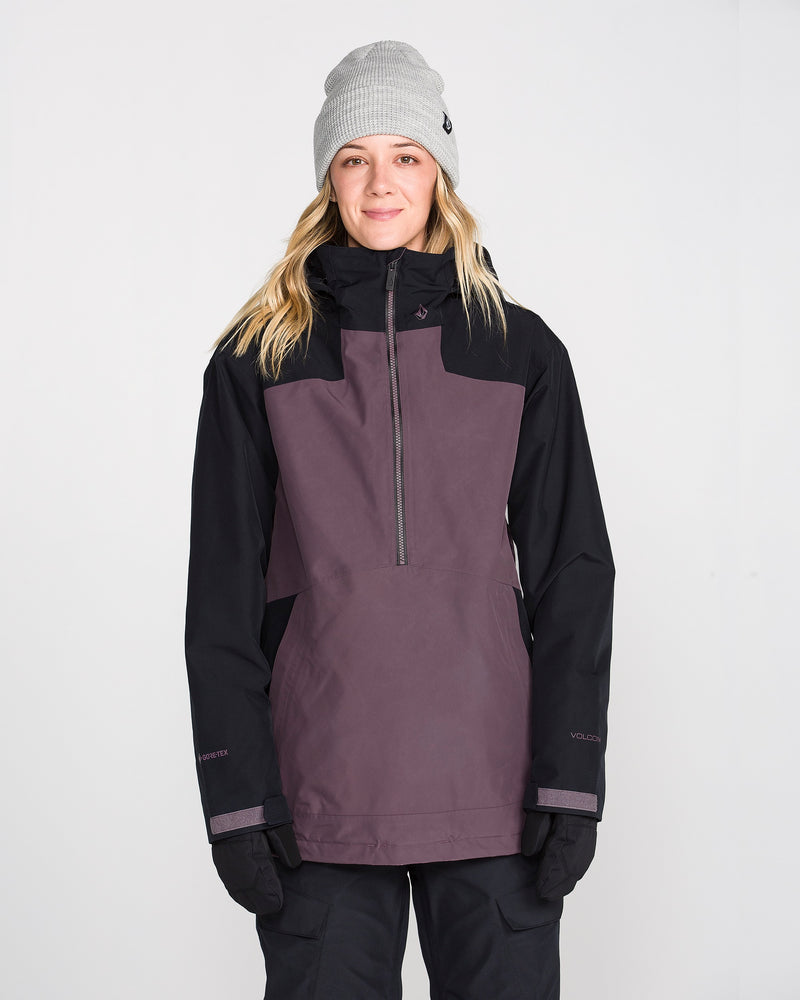 A person wearing a gray beanie, black gloves, and the Volcom Women’s Rowan Insulated Gore Pullover stands facing forward against a plain white background.