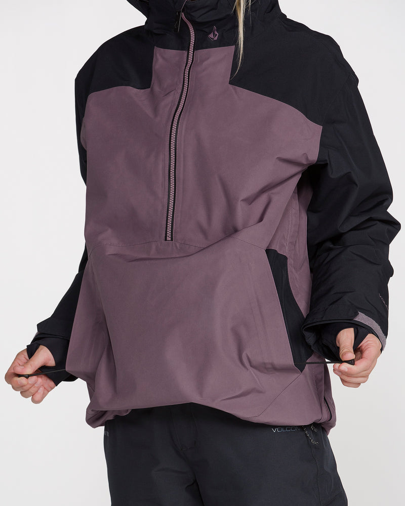 A person wearing the Volcom Women’s Rowan Insulated Gore Pullover—an insulated, waterproof ski jacket featuring a purple and black design with black sleeves, a front zipper, large front pocket, and hood for added warmth and protection—pulls on the side of the jacket.
