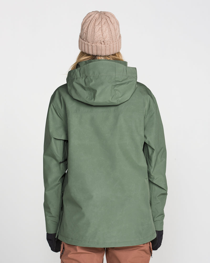 A woman is seen from behind wearing the Volcom Women’s Rowan Insulated Gore Pullover in light green, paired with a beige knit beanie and brown pants, set against a plain white background.