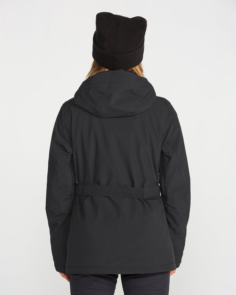 A person wearing the Volcom Women’s Alpine All Day Insulated Jacket in black, featuring a hood, along with a black hat, is seen from behind standing against a plain white background.