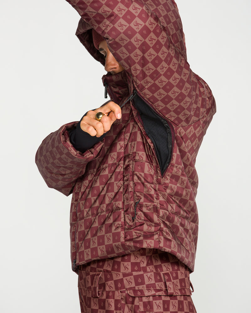 A person wearing the Volcom Women’s Avalon Puff Jacket—a women’s jacket with a patterned maroon design, recycled insulation, and a repeating Volcom logo—unzips an underarm zipper. Their face is partially covered by the jacket.