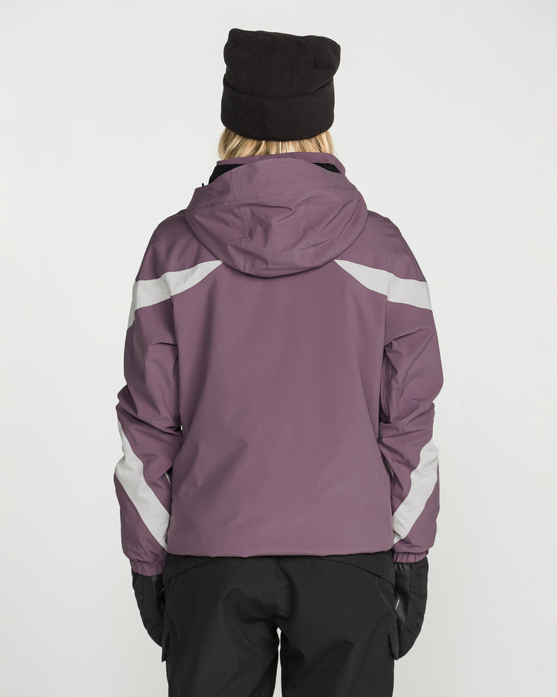 A person is seen from behind against a plain white background, wearing the Volcom Women’s Shelter 3D Stretch Jacket in purple, along with a black beanie, black gloves, and black pants.