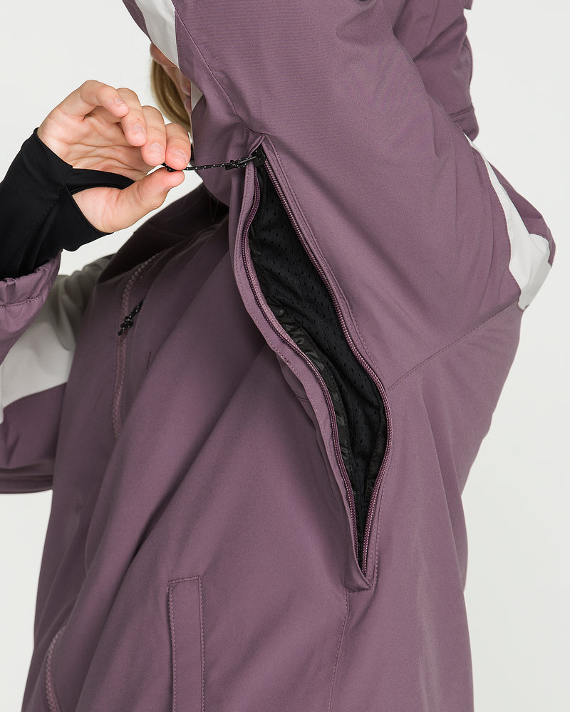 A person unzips the underarm ventilation of the Volcom Women’s Shelter 3D Stretch Jacket in purple with white accents, revealing the black mesh lining inside.