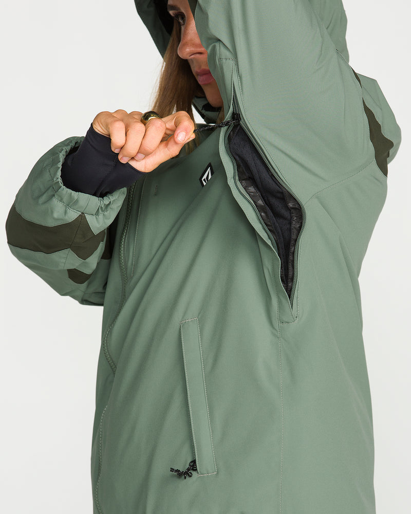 A person wearing the Volcom Women’s Shelter 3D Stretch Jacket in light green unzips an underarm ventilation opening, revealing the black inner lining. Only part of their face is visible.