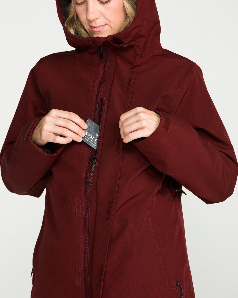 A person wearing the Volcom Women’s Stoney Shadow Insulated Jacket in maroon inserts a small card into the chest zipper pocket.