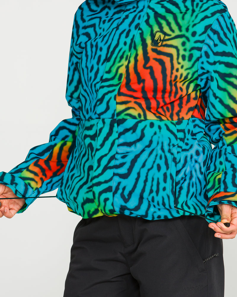 A person is wearing the Volcom Women’s Bolt Insulated Jacket, featuring a vibrant, multicolored zebra print with blue, green, and orange stripes, paired with black pants. Only the lower face, torso, and one hand are visible.
