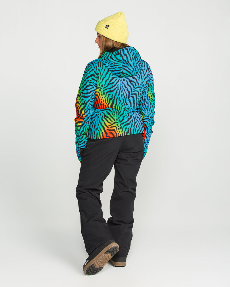 A person stands with their back to the camera, wearing a yellow beanie and the Volcom Women’s Bolt Insulated Jacket featuring a colorful zebra pattern in green, blue, orange, and black, paired with black pants against a plain white background.