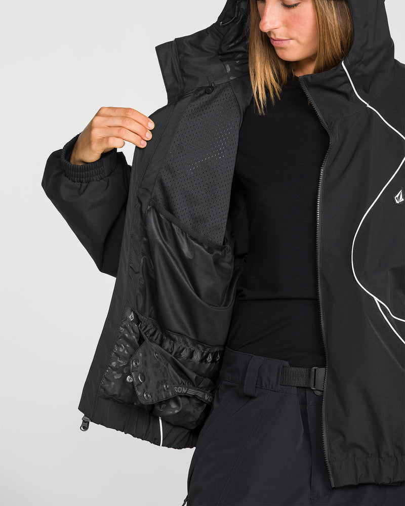A person in a black, baggy fit Volcom Unisex Liftline 20K Jacket and pants shows the inside of their jacket, revealing multiple mesh and fabric pockets. The snowboarding jacket features a hood, white piping detail, and offers 20K waterproof protection for ultimate performance on the slopes.