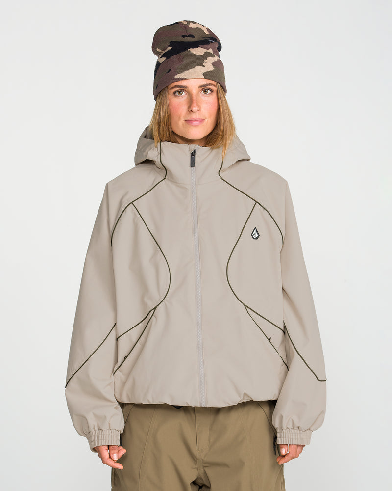 A person wearing the Volcom Unisex Liftline 20K Jacket in taupe with a baggy fit and black piping, paired with matching khaki pants and a brown camouflage beanie, stands against a plain white background facing forward with a neutral expression.