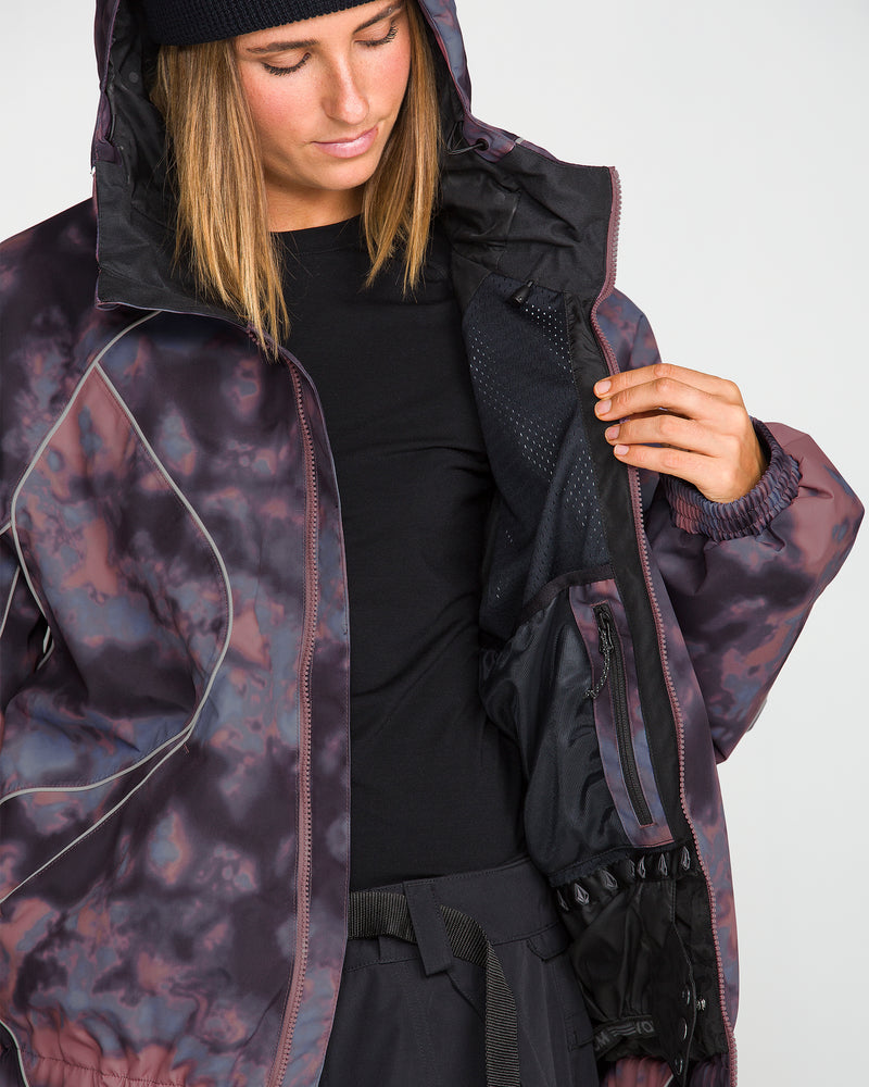 A person wearing the Volcom Unisex Liftline 20K Jacket—a baggy fit snowboard jacket with a hooded, patterned design—looks down and opens the jacket to reveal its mesh inner pocket, 20K waterproof lining, and zippered compartments.