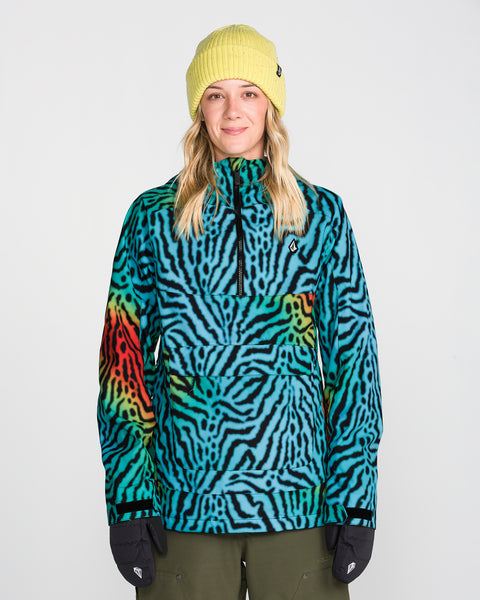A person wearing a yellow beanie, black gloves, and the Volcom Women’s Harlan Pullover—a blue, green, and red zebra-striped jacket featuring V-Science 2-Layer construction and PFAS-free DWR—stands facing forward against a plain white background.
