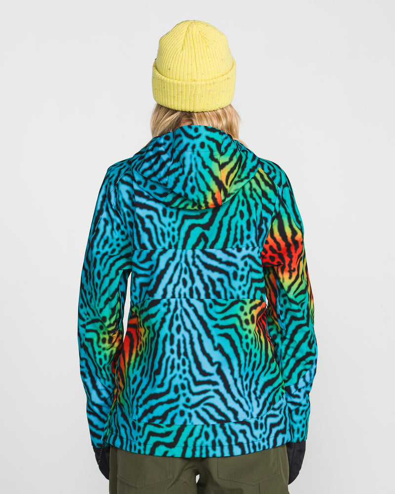 A person wearing a yellow beanie and the Volcom Women’s Harlan Pullover—a colorful blue, green, and orange zebra-print jacket featuring PFAS-free DWR—stands facing away from the camera with their hands at their sides.