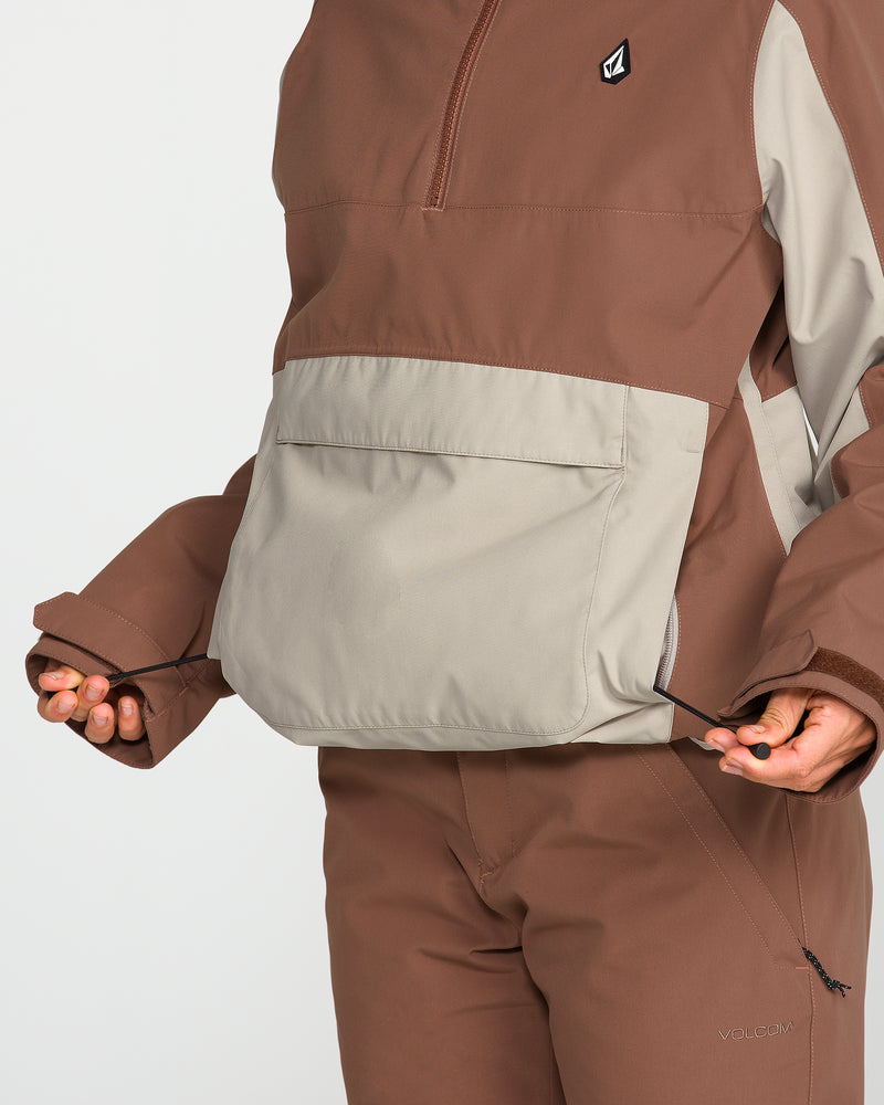 A person wearing the Volcom Women’s Harlan Pullover in brown and beige adjusts the drawstrings on the front pocket of their jacket, with only their lower face and torso visible.