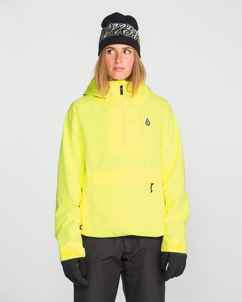 Wearing the Volcom Women’s Harlan Pullover in yellow, paired with black pants, gloves, and a black beanie, a person stands facing forward against a plain light background.