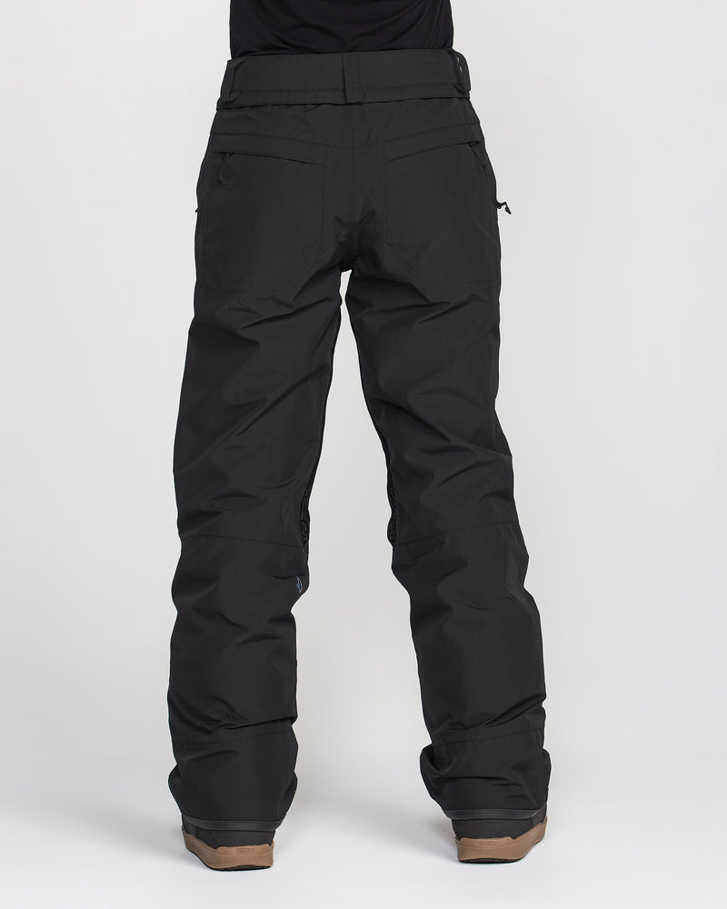 A person is photographed from the back against a plain white background wearing Volcom Women’s Kanyon Insulated Gore Pants in black and brown boots.