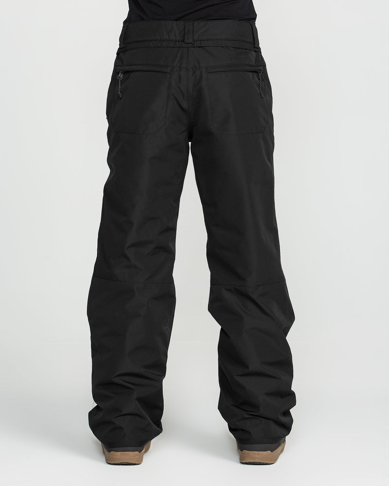 A person wearing Volcom Women’s Coldfront Insulated Baggy Pants with V-Science 2-Layer construction and brown boots, standing with their back to the camera against a plain white background.