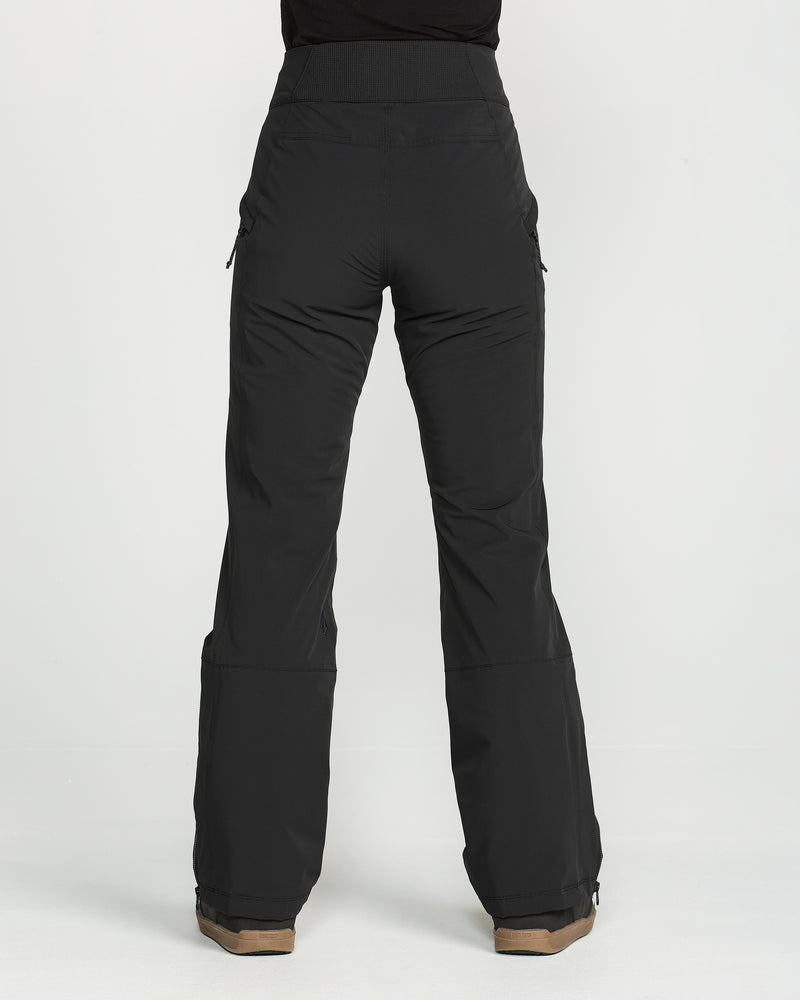A person wearing the Volcom Women’s Alpine All Day Insulated Pants—high-waisted, black, wide-leg pants with a high-rise fit—and brown shoes is standing against a plain white background, facing away from the camera.