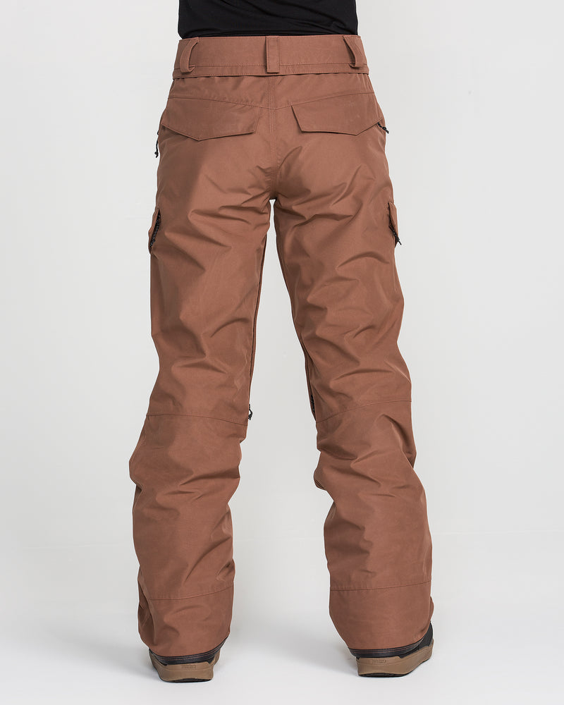 A person stands with their back to the camera against a plain white background, wearing brown Volcom Women’s Stonelark Gore-Tex Pants and matching brown shoes. The pants, crafted from durable waterproof material, feature flap pockets for utility and style.