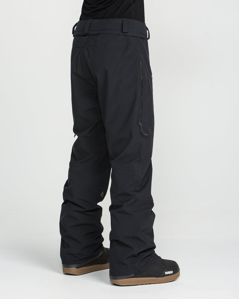A person is shown from the back at an angle, standing on a white background, wearing Volcom Women’s Karat Stretch 30K Pants with V-Science 2-Layer construction in black and matching black winter boots.