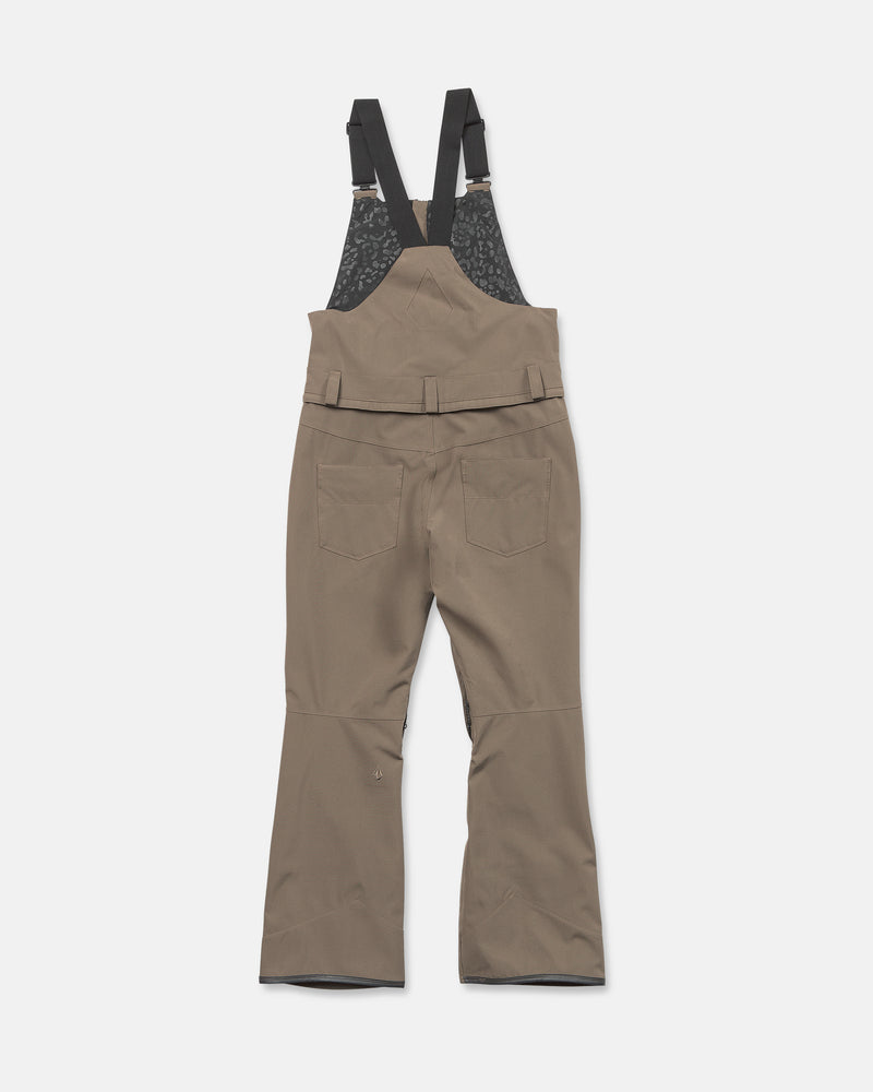 The Volcom Women’s Swift Bib, made from recycled fabric, features black adjustable shoulder straps, two back pockets, flared legs, and a textured black lining on the upper back section. Shown here in brown against a white background.