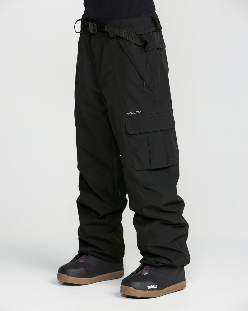 A person is wearing Volcom Unisex Liftline 20K Pants—loose black snow pants with cargo pockets and a belt, featuring the VOLCOM logo. The pants are made from recycled fabric ski pant material and are paired with black snow boots. The background is plain white.