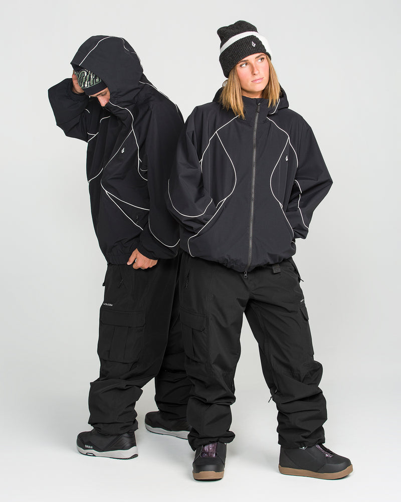 Two people in black winter outfits with white piping stand side by side. One faces forward with hands in pockets, wearing a beanie, while the other looks down, adjusting their hood. Both wear Volcom Unisex Liftline 20K Pants and snow boots—perfect for staying dry and comfortable on the slopes.