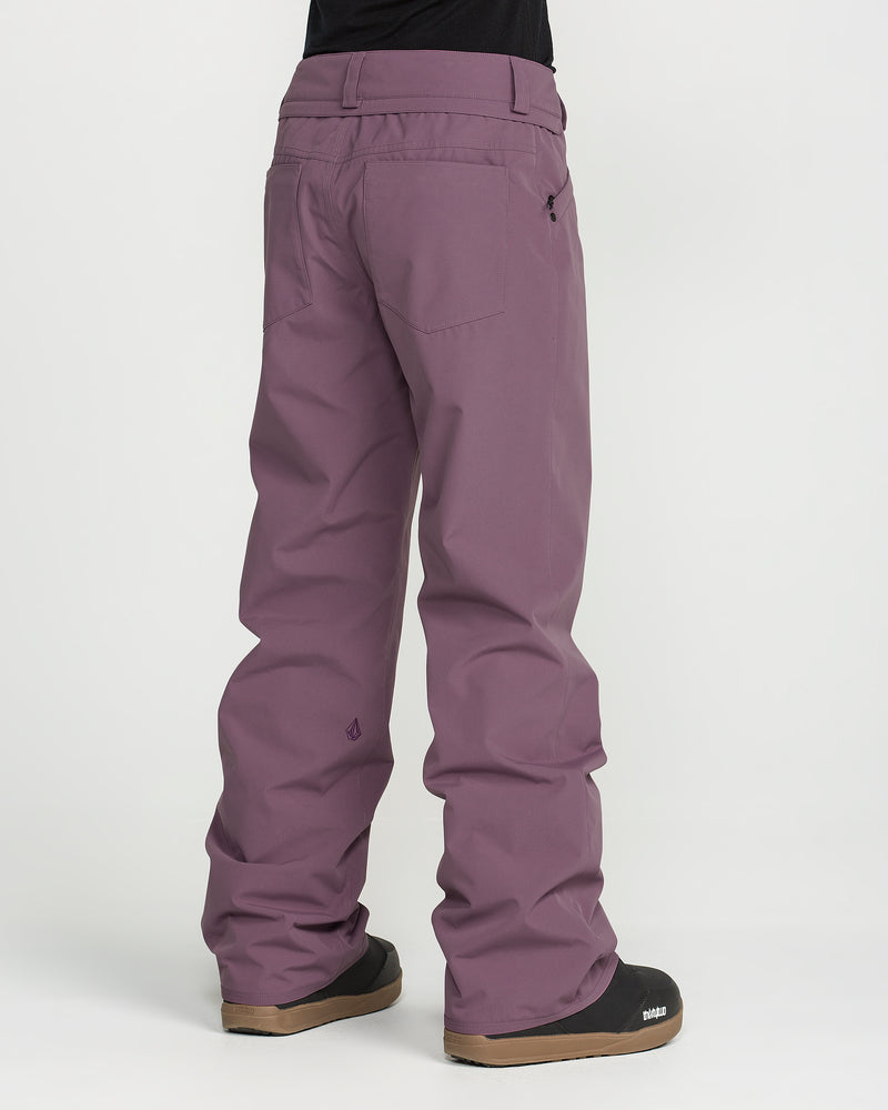 A person is shown from the back against a plain white background, wearing loose-fitting purple Volcom Women’s Stoned Pants and black shoes.