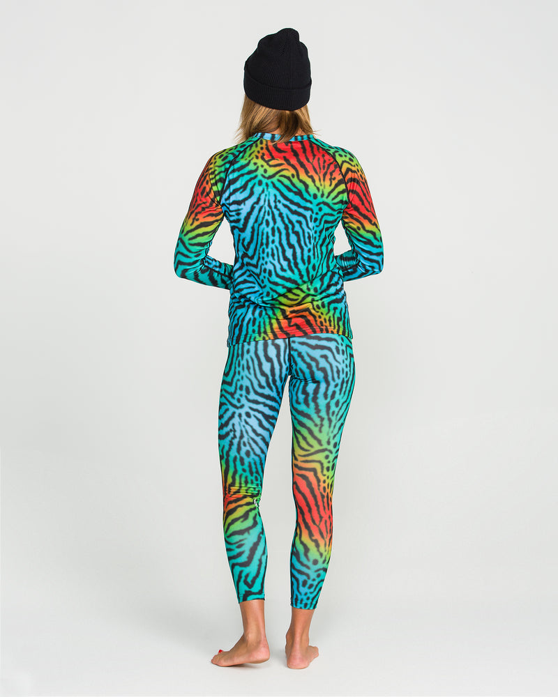 Barefoot and facing away against a plain white background, a person wears a black beanie along with the Volcom Women’s W V-Science Pants—a vibrant, multicolored matching top and women’s pant set featuring an abstract zebra print pattern in quick-dry knit fabric.