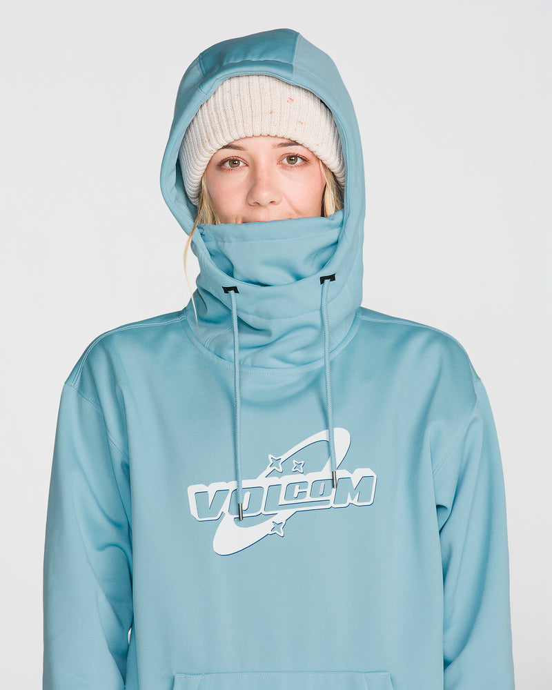 A person is pictured in a light blue Volcom Women’s Riding Hydro Pullover, featuring a high neck and drawcord hood worn up, paired with a white knit beanie. Crafted from hydrophobic fleece for added comfort and functionality, the scene is set against a plain, light-colored background.