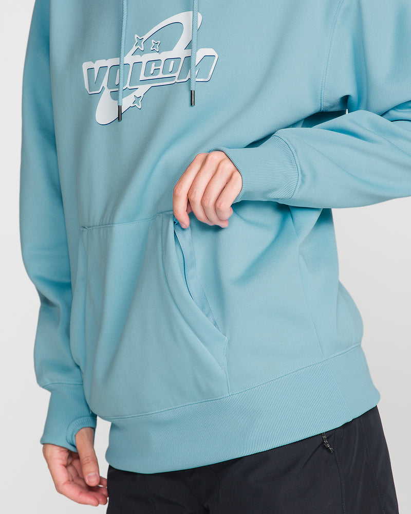 A woman wearing the Volcom Women’s Riding Hydro Pullover—a light blue hydrophobic fleece hoodie featuring a drawcord hood and front pocket—places one hand inside the pocket, with the lower half of her face not visible.