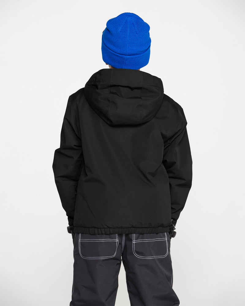 A person is seen from behind, standing against a plain white background, wearing a blue knit hat, dark pants with visible white stitching, and a black Volcom Kids’ Youth Chaos Insulated Jacket with recycled insulation.