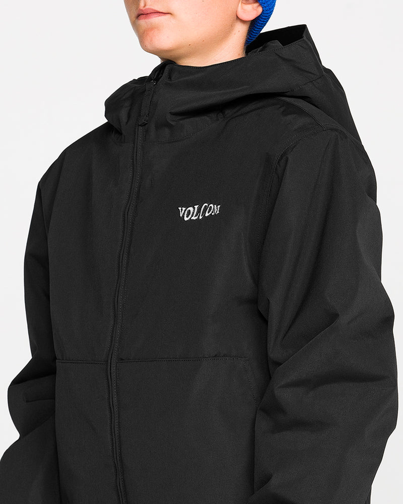 A person wearing a black Volcom Kids’ Youth Chaos Insulated Jacket with recycled insulation and weather defense, featuring a hood and a blue beanie, faces slightly to the side against a plain background.